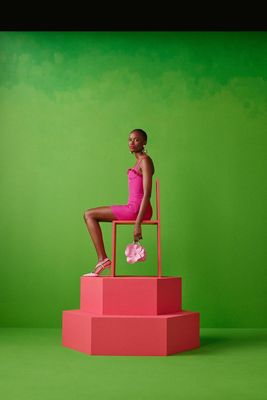 a woman in a pink dress sitting on a pink chair