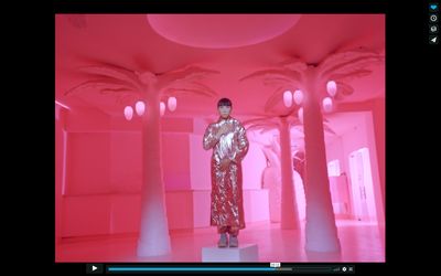 a woman in a gold dress standing in a pink room