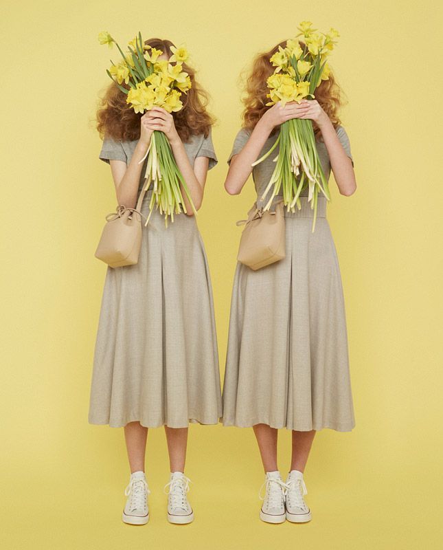 two women with flowers in their hair are standing in front of a yellow background