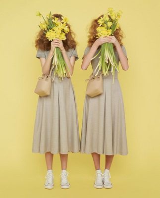 two women with flowers in their hair are standing in front of a yellow background