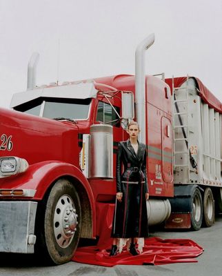 a woman standing next to a large red truck