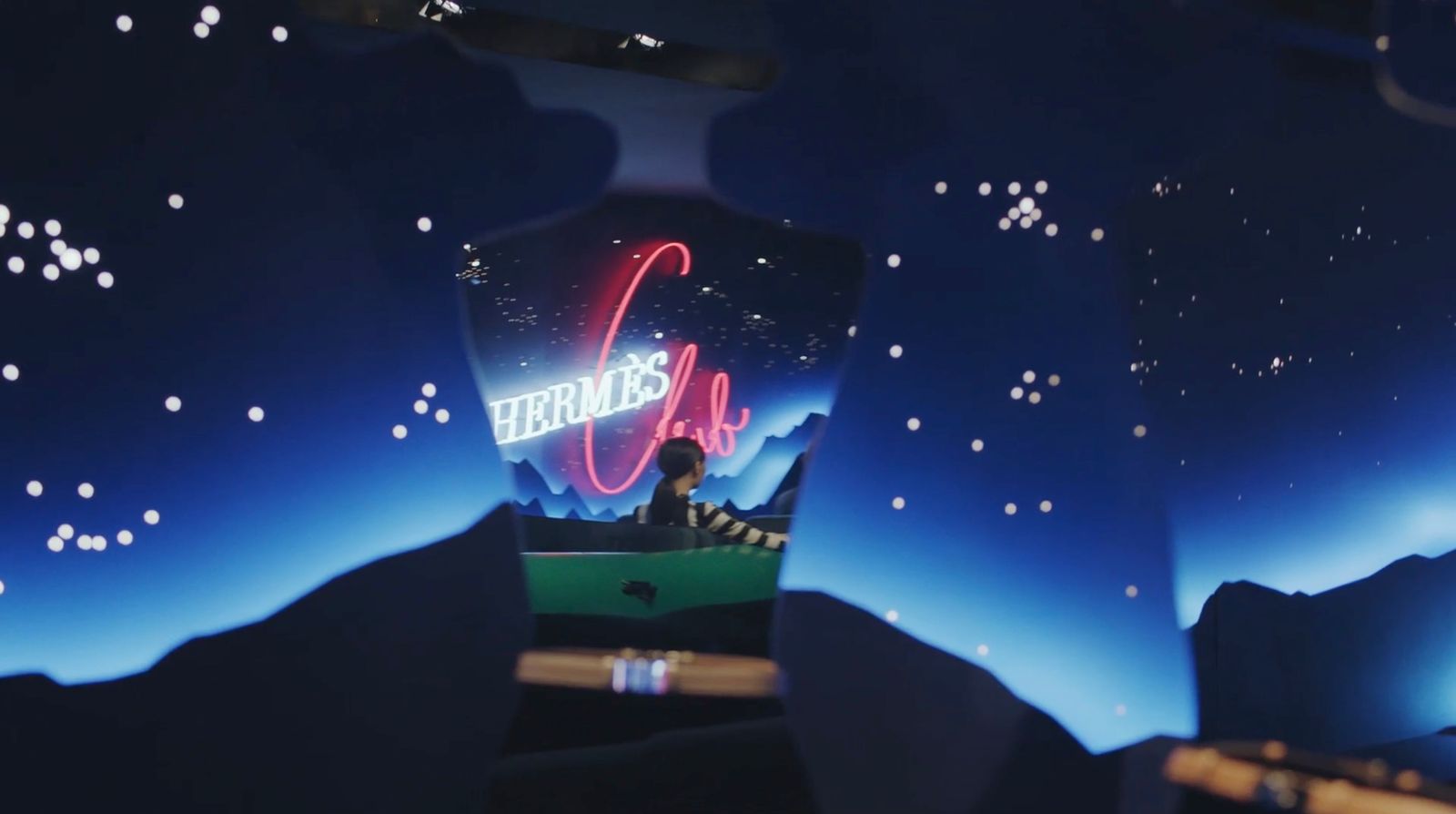 a person sitting in a green chair in front of a neon sign