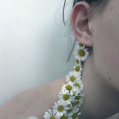 a close up of a person wearing a necklace with flowers on it