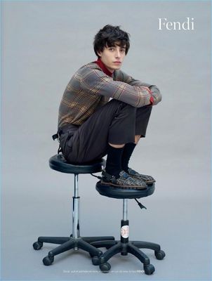 a young man sitting on top of a stool