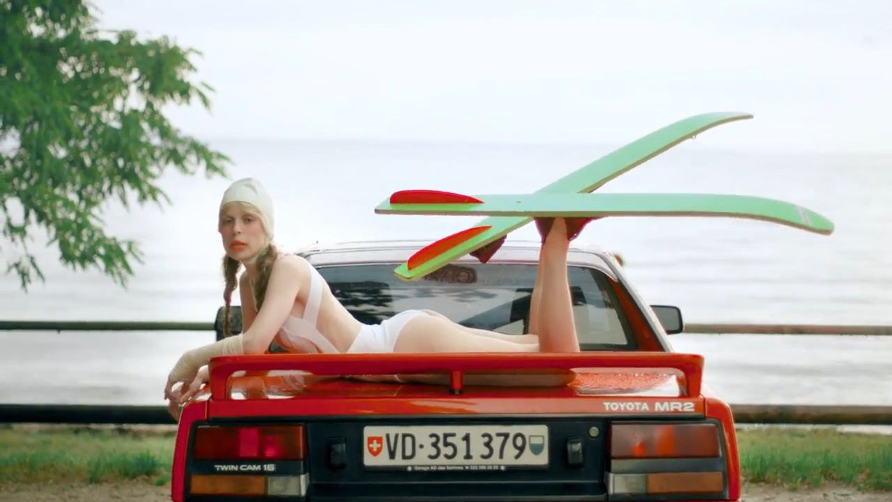 a woman laying on the back of a red car