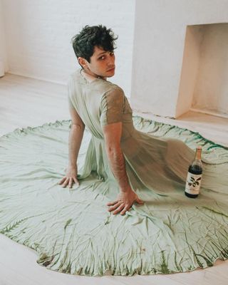 a woman sitting on the floor with a bottle of wine