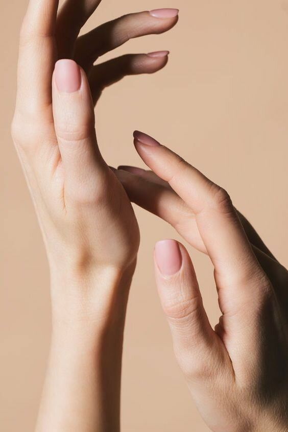 a woman's hands with pink manicures holding something