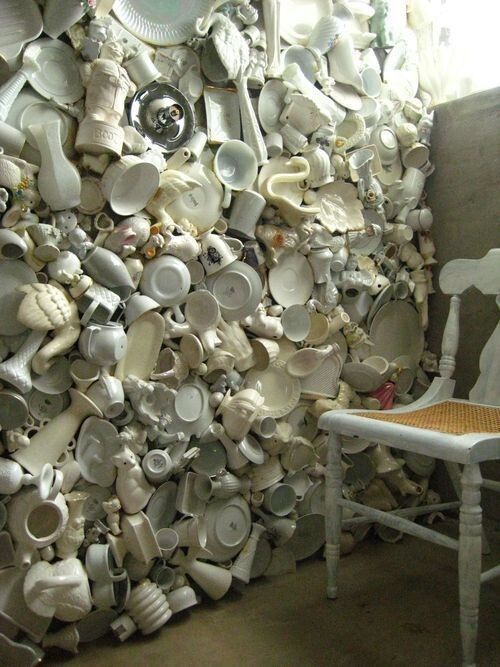 a white chair sitting in front of a wall of plates and pans