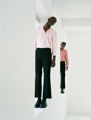 a man in a pink shirt and black pants