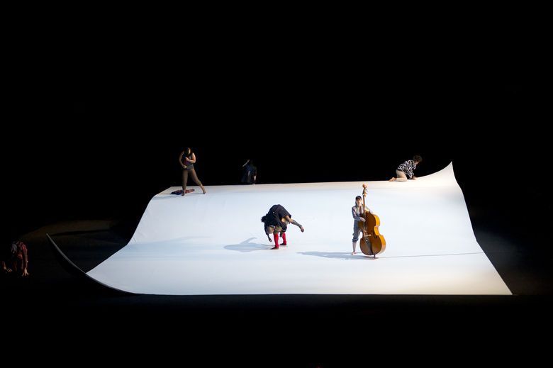 a group of people standing on top of a white sheet