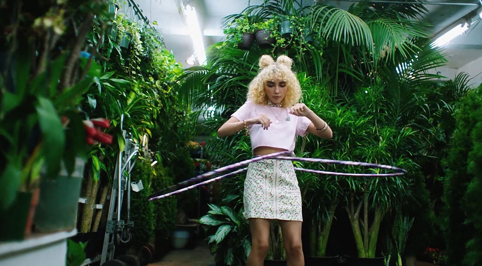 a woman in a pink shirt and white skirt playing with a hula hoop