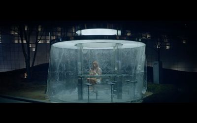 a woman sitting at a table inside of a glass enclosure