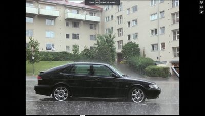 a black car is parked in the rain