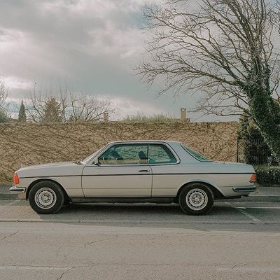 a car parked in a parking lot next to a tree