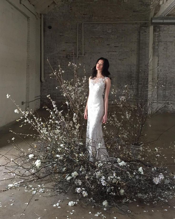 a woman standing in front of a bunch of flowers