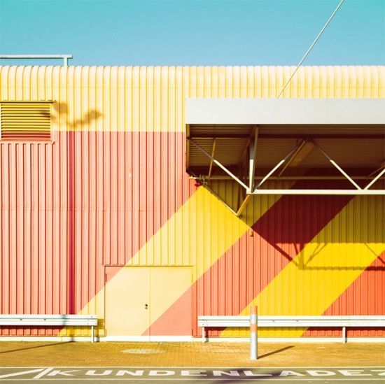 a yellow and red building with a bench in front of it