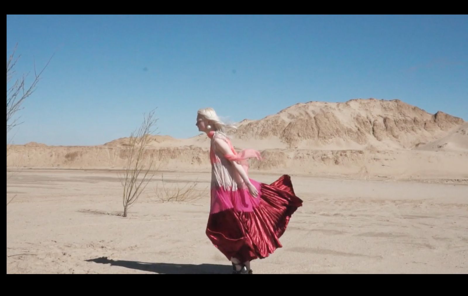 a woman in a pink and white dress in the desert