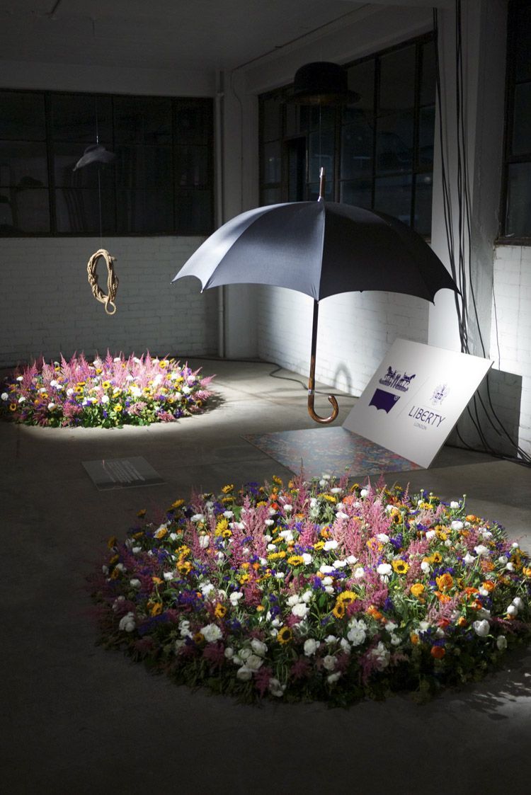 a black umbrella sitting on top of a flower bed