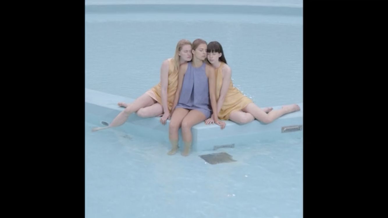 three girls sitting on the edge of a swimming pool