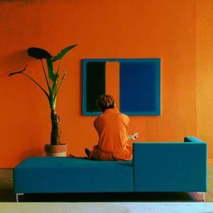 a person sitting on a blue couch in front of an orange wall