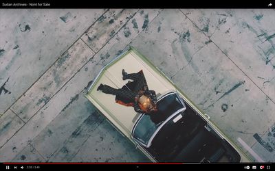 an aerial view of a man in a suit standing on top of a car