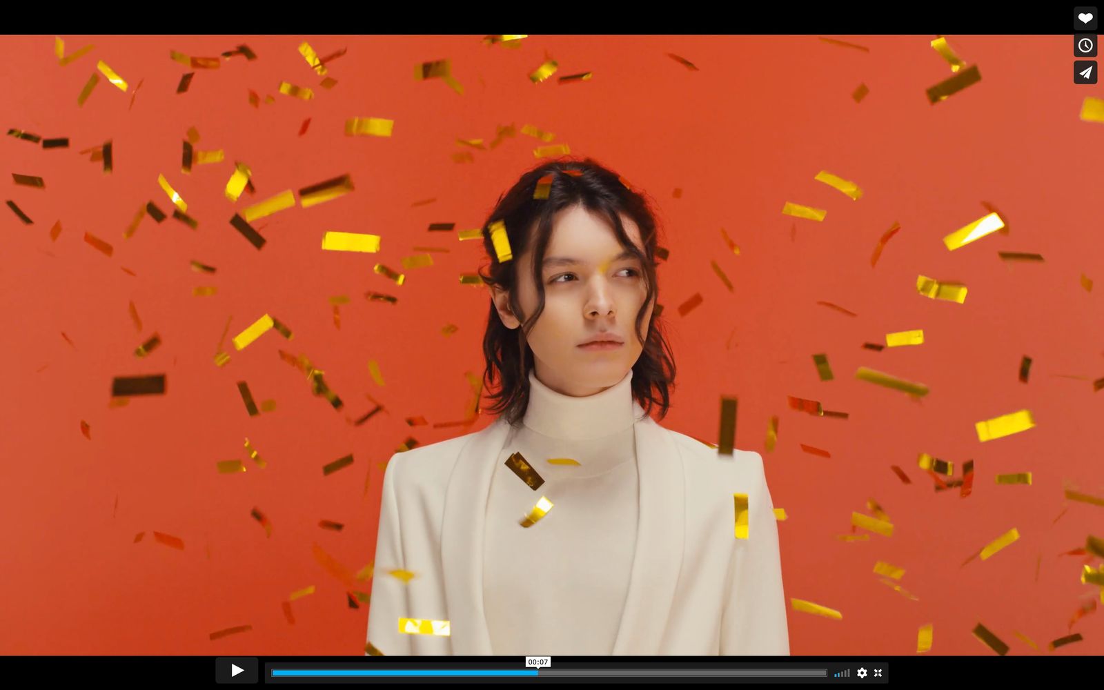 a woman standing in front of a red wall with gold confetti