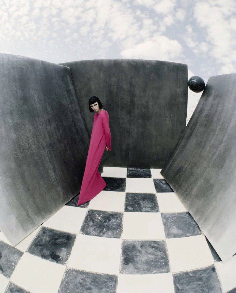 a woman in a pink dress standing in a room with a checkered floor