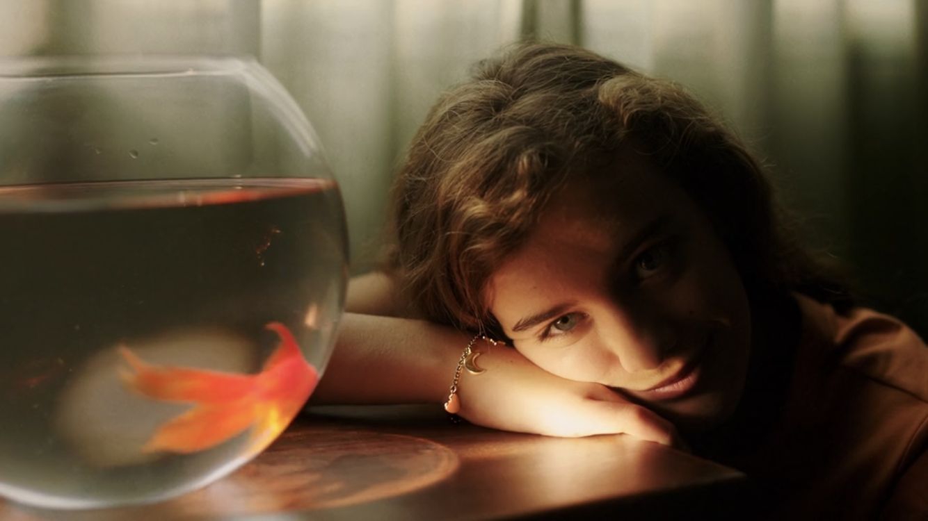 a woman leaning on a table next to a fish bowl