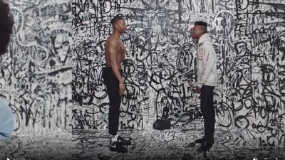 two men standing in front of a wall covered in graffiti