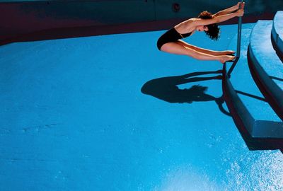 a woman in a black swimsuit diving into a pool