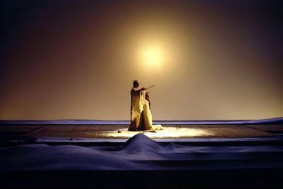 a woman standing in the snow at night