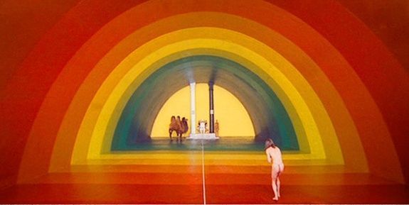 a person standing in front of a painting of a rainbow