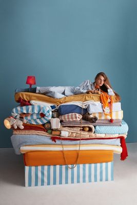 a woman laying on top of a pile of clothes