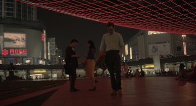 a group of people standing on a sidewalk at night