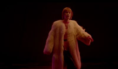 a woman in a fur coat is standing in the dark