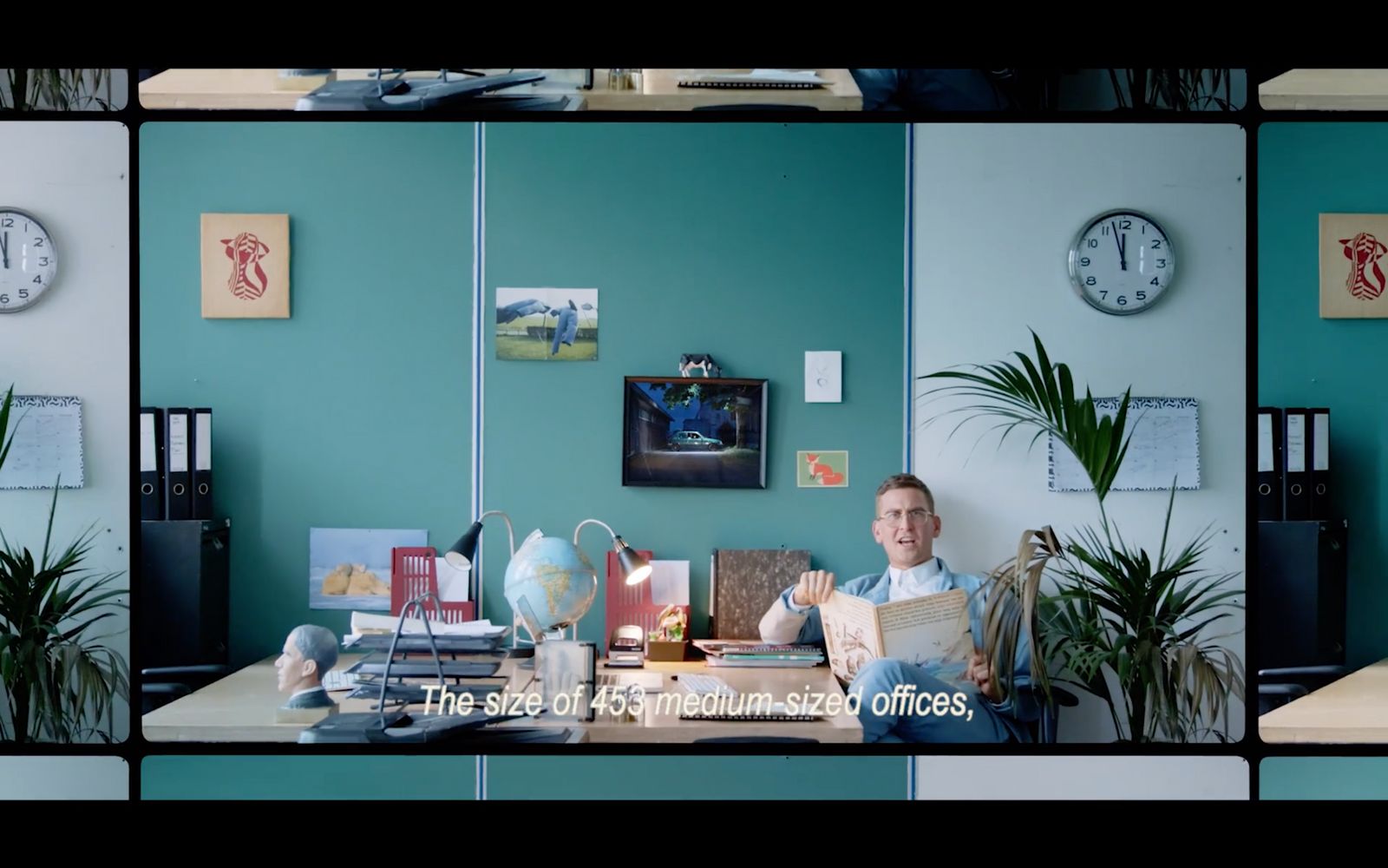 a man sitting at a desk in front of a clock