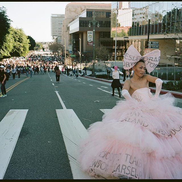 a woman in a pink dress walking down a street