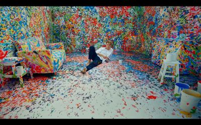 a man kneeling down in a room filled with paint