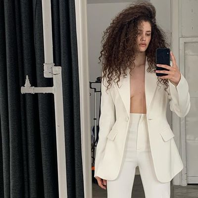 a woman in a white suit taking a selfie