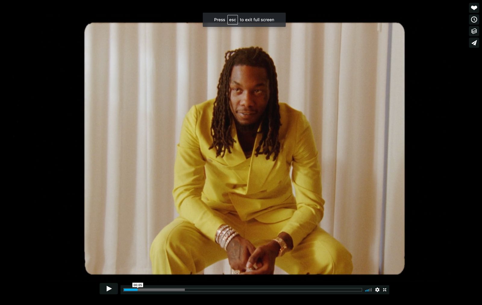 a man in a yellow suit sitting on a chair