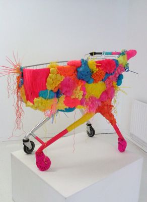 a shopping cart covered in colorful fabric on a white surface