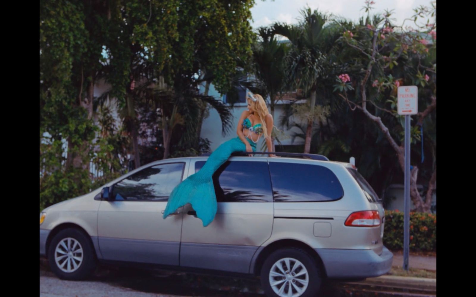 a woman is sitting on the hood of a car