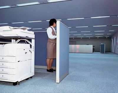 a woman standing in a room next to a printer