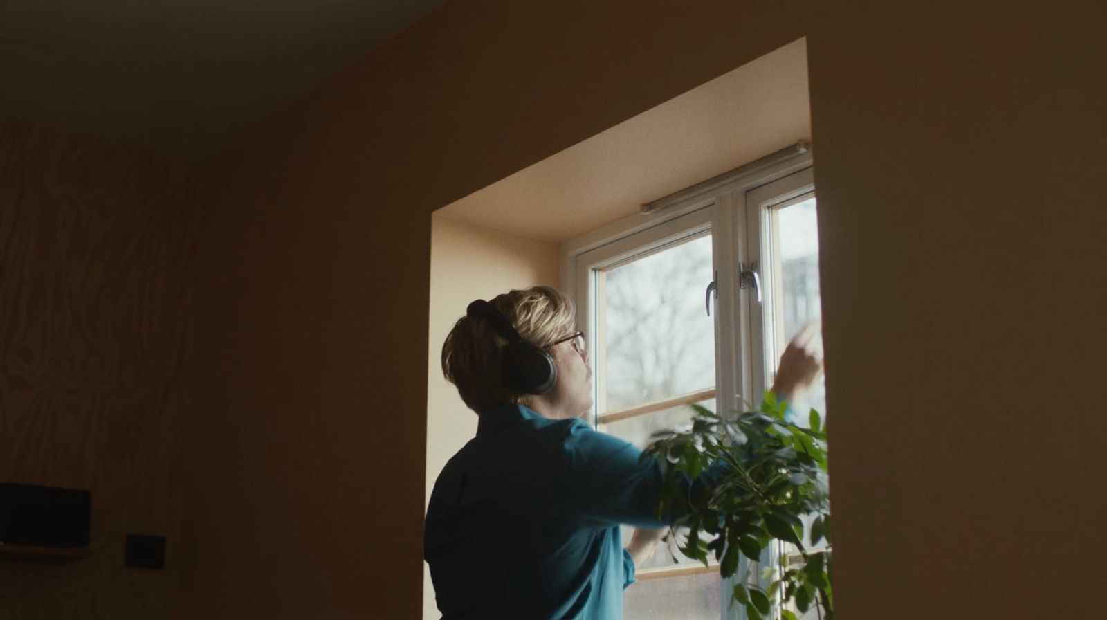 a woman standing in front of a window next to a plant