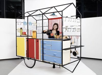 a woman standing behind a cart made out of drawers