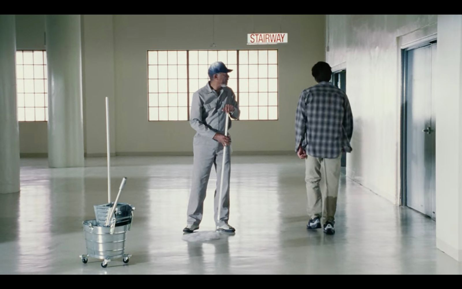 two men standing in an empty room with luggage