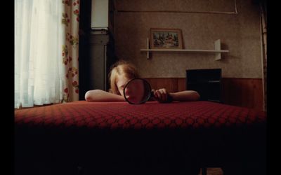 a girl laying on a bed with a magnifying glass