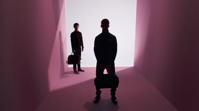 two people standing in a room with a suitcase