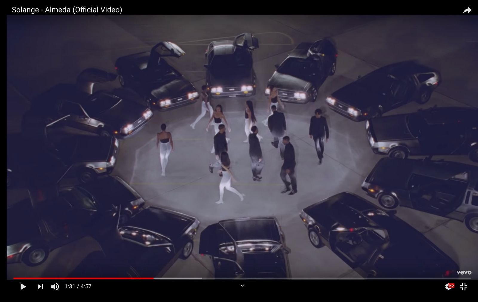 a group of people walking around a circle of parked cars