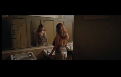 a woman standing in front of a mirror in a bathroom